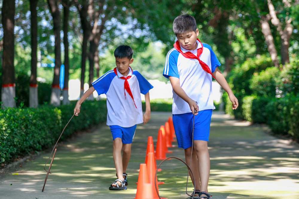 《滚铁环》2023年7月18日，山东省滕州市大坞镇凫山假期快乐成长营的孩子们在做滚铁环游戏。