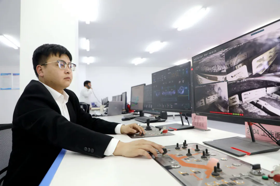 图为永明煤矿综采工区技术员孟伟在地面集控中心通过远程控制装置操控井下设备2.jpg
