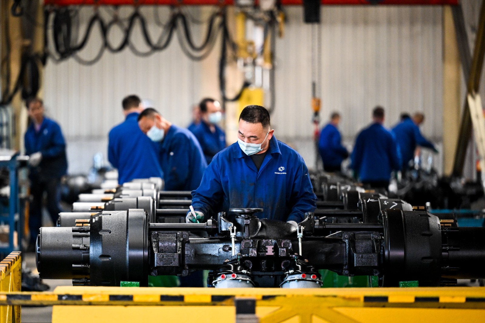 包头北奔重汽桥箱有限公司内，工人在装配车桥总成。