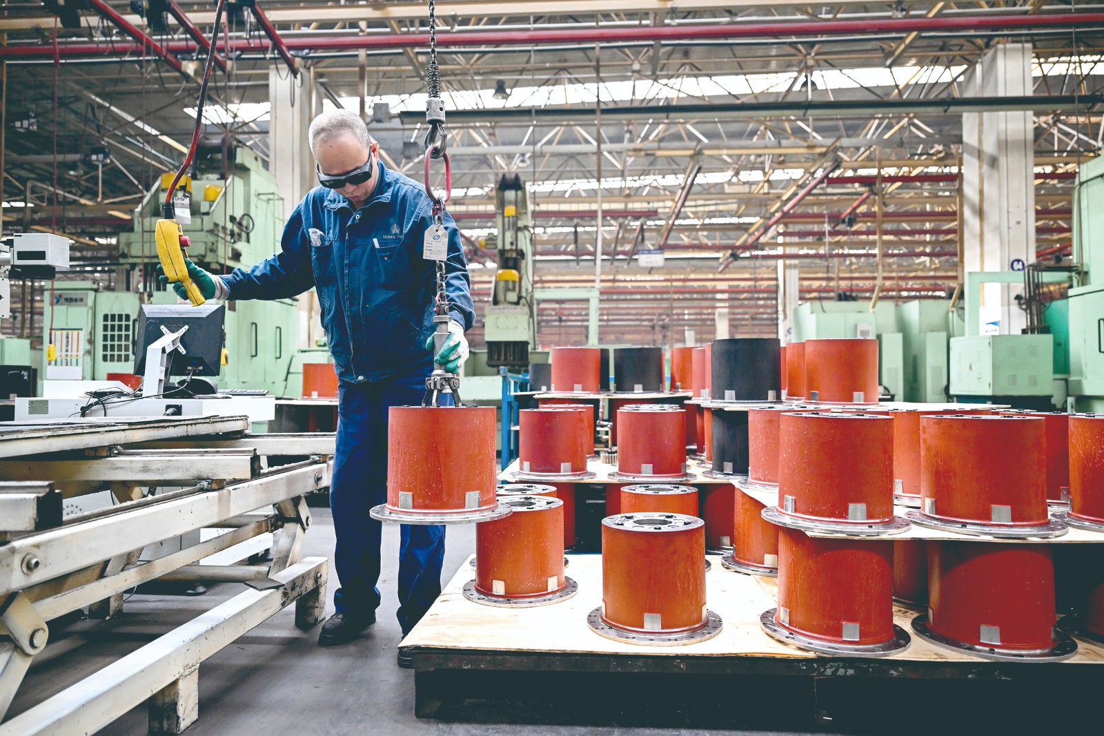 包头北奔重汽桥箱有限公司内，工人在吊装零件。