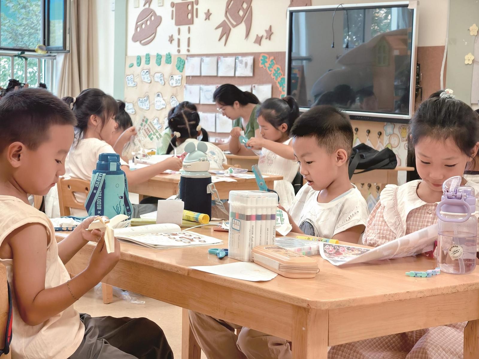 戎美幼儿园的孩子们在老师陪伴下做手工。